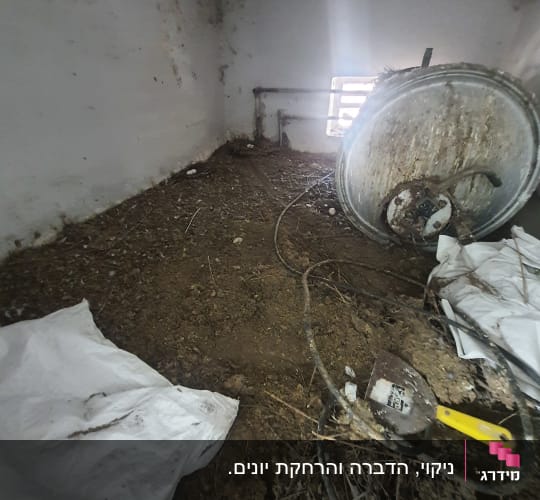 חדר עם קיר לבן, כלי עבודה וחפצים על הרצפה